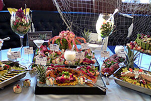 Buffet. Diverse Teller mit Speisen werden auf einem Tisch präsentiert.