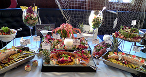 Buffet. Diverse Teller mit Speisen werden auf einem Tisch präsentiert.